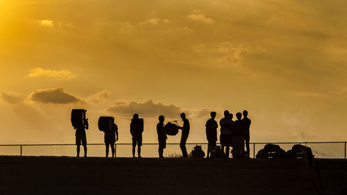 Silhouette people standing against sky during sunset