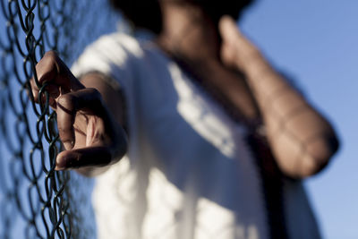 Midsection of woman standing by a fence