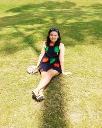 Portrait of a smiling young woman sitting on field