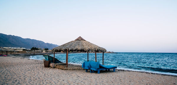 Deck chairs on beach against clear sky