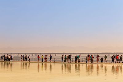 Silhouette people by sea against sky during sunset