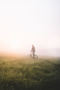 Full length of man with bicycle on field during foggy weather