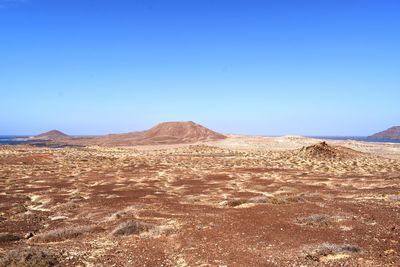 Scenic view of desert against clear blue sky