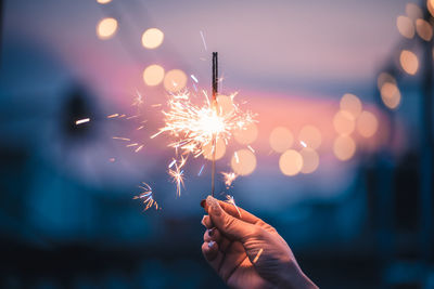 Woman holding sparkler at night