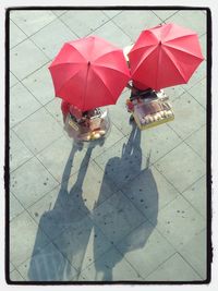 Low section of woman holding umbrella on footpath