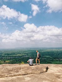 Rear view of friends standing on landscape against sky