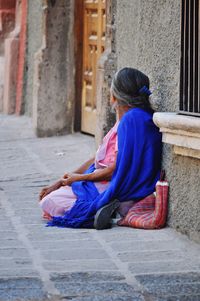 Side view of woman sitting on street in city