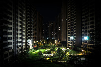 Illuminated street amidst buildings in city at night