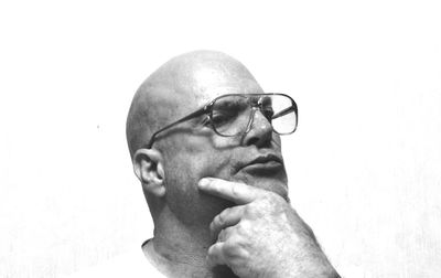 Close-up of thoughtful man wearing eyeglasses with hand in chin against white background