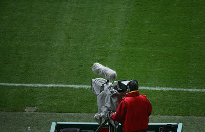 Rear view of man with television camera on sports field