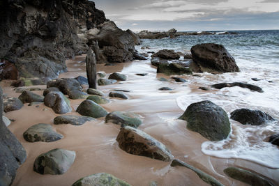 Rocks on beach against sky