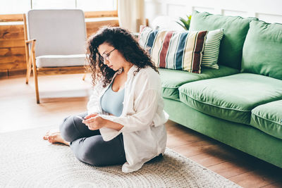 Side view of woman sitting on bed at home