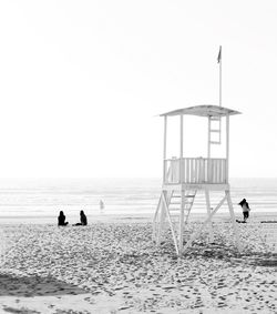 Silhouette people on beach against clear sky