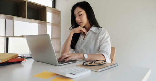 Mid adult woman using mobile phone while sitting on table