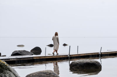 Woman walking on jetty against sky