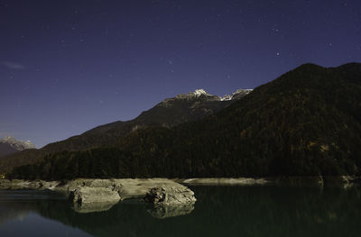 Scenic view of lake and mountains against clear sky at night