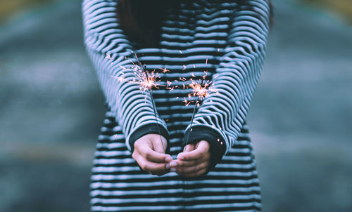 Midsection of woman holding lit sparkler