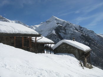 Snow covered house and mountains against sky