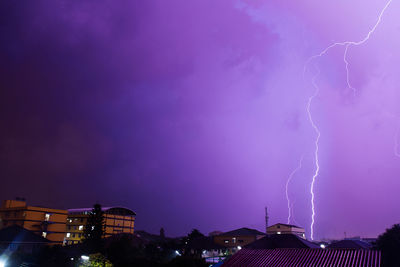 Lightning over buildings against dramatic sky at night