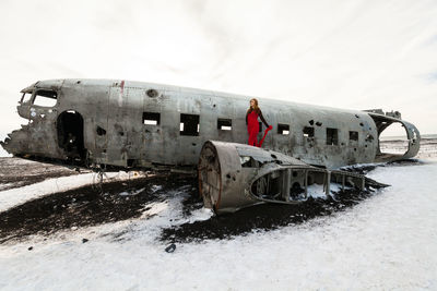 Abandoned airplane on snowy field against sky