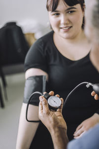 Smiling female patient looking at male doctor examining blood pressure in medical clinic