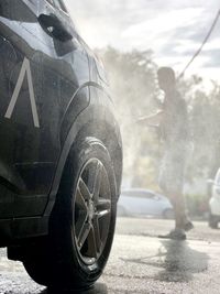 Man standing by car on road in city