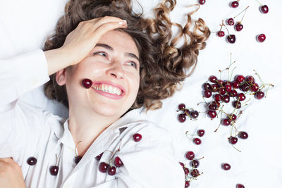 Happy woman with fruits lying down on white background