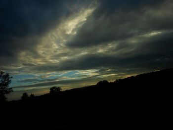 Low angle view of storm clouds over silhouette landscape