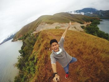 Portrait of smiling young woman by mountain against sky