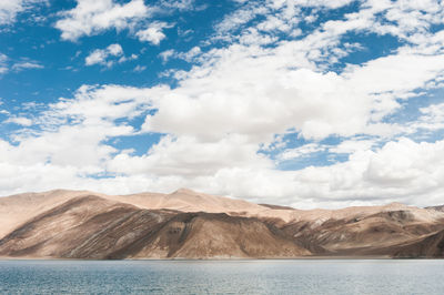 Scenic view of pangong lake by mountains against cloudy sky