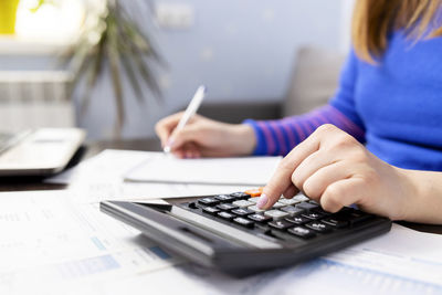 Midsection of woman using calculator at desk in office