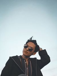 Portrait of young man wearing sunglasses against sky