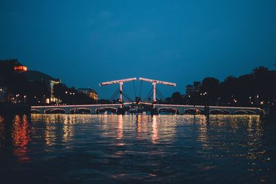 Illuminated bridge over river against sky at night