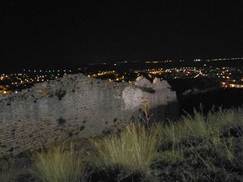 Illuminated cityscape by sea against sky at night