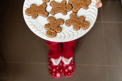 Low section of boy holding gingerbread cookies at home