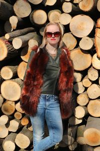 Woman standing against log stacks