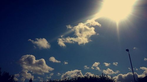 Low angle view of sun shining through clouds