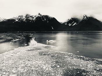 Scenic view of lake by snowcapped mountains against sky