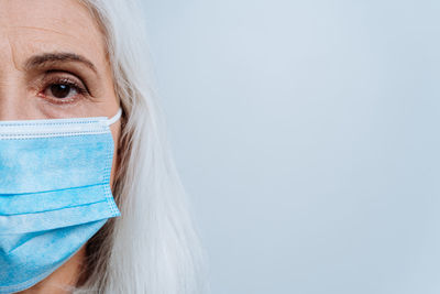 Portrait of woman wearing mask against blue background