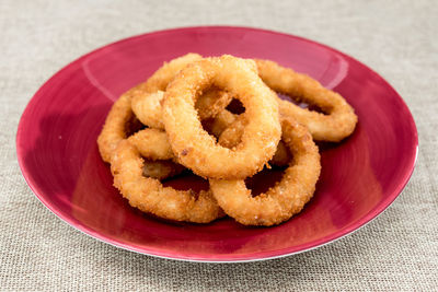 High angle view of onion rings served in plate on jute fabric
