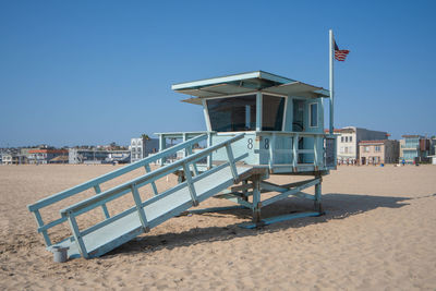 Lifeguard hut on beach against clear blue sky