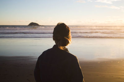 Rear view of woman at beach against sky