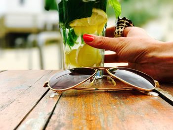 Cropped hand of woman holding drink at wooden table