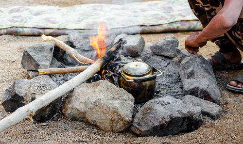 Low section of man preparing food on bonfire