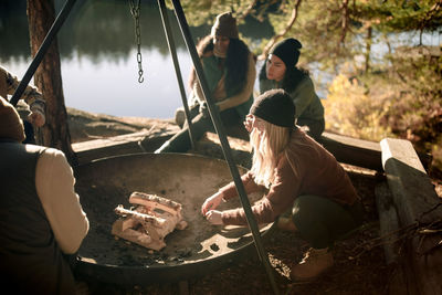 Female friends talking to each other while preparing firepit during camping