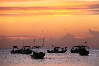 Boats sailing on sea against sky during sunset