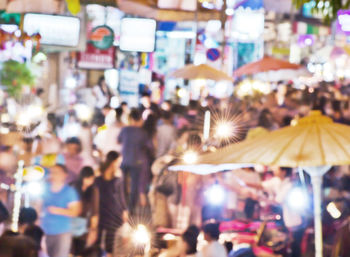 Group of people at illuminated street in city at night