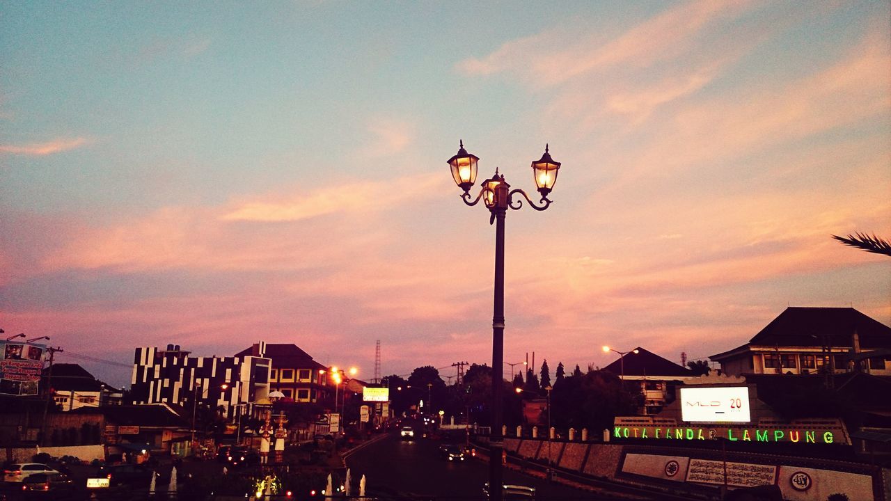 sky, sunset, building exterior, street light, architecture, built structure, transportation, cloud - sky, lighting equipment, mode of transport, illuminated, car, street, cloudy, land vehicle, city, dusk, low angle view, orange color, cloud