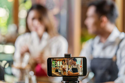 Man photographing woman using mobile phone