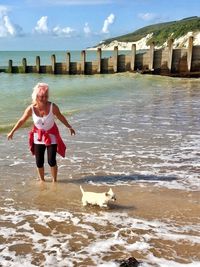 Smiling woman with puppy standing in sea